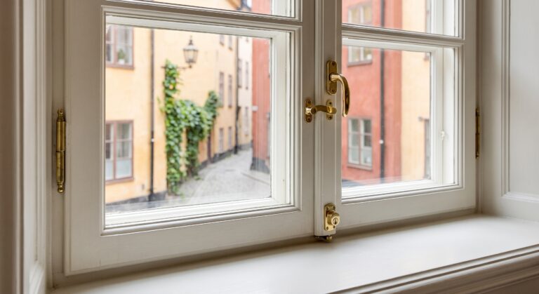 Fönstersnickare i Stockholm monterar diskret fönsterlås på ett renoverat träfönster